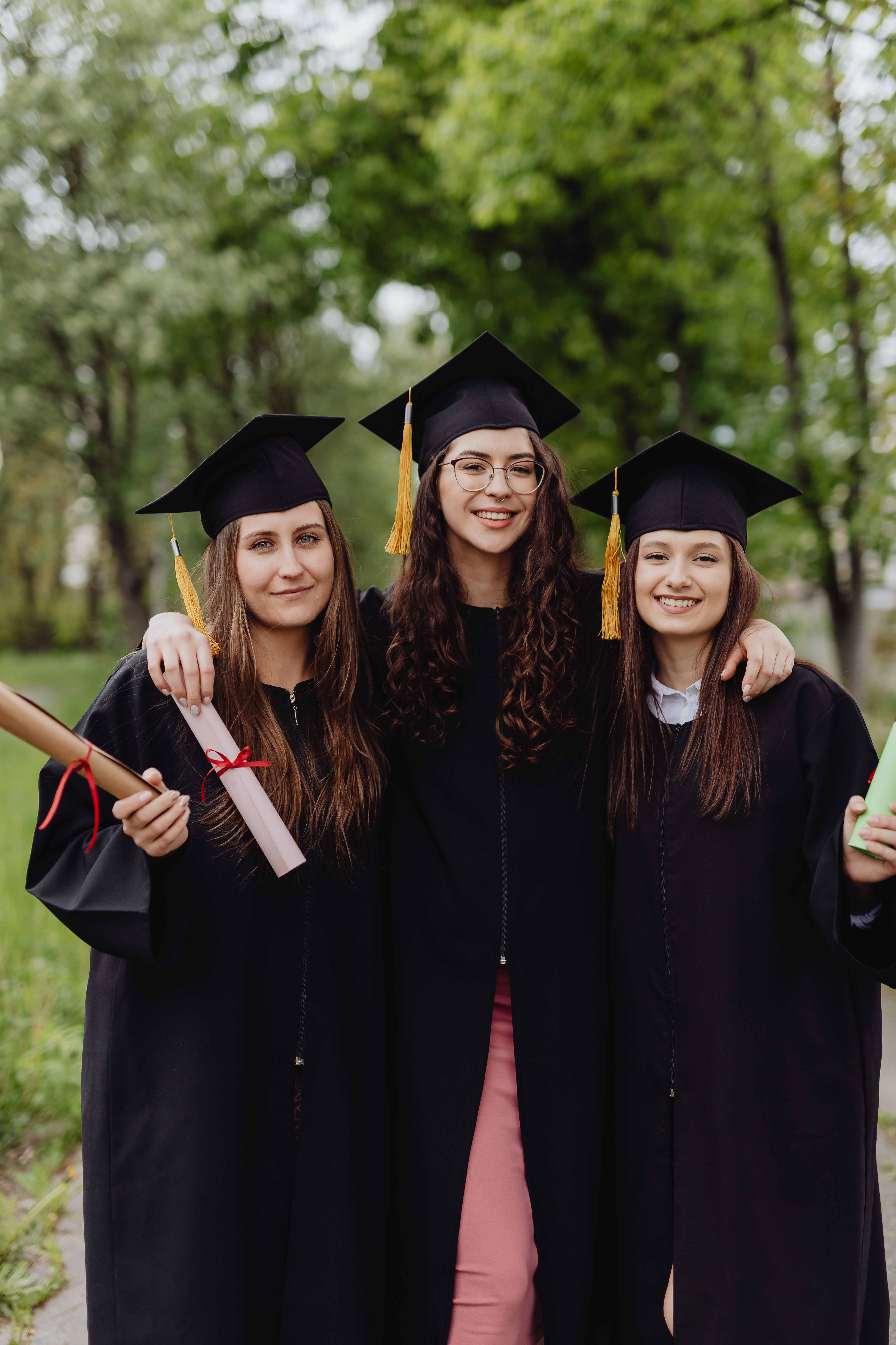 Comparison of three academic cap styles: a black mortarboard, a rounded velvet tam, and a Tudor bonnet